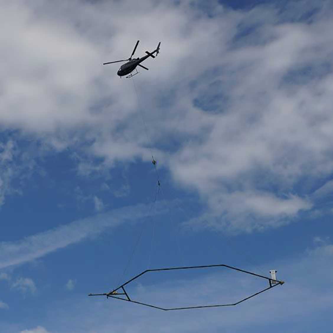 Figure 9. Helicopter towing a geophysical device as part of an electromagnetic and magnetic survey to collect TDEM data (USGS).