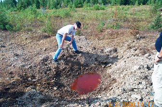 Figure 1.1.  Pink water in crater formed by the dissolution of TNT from a 500-lb. bomb that partially detonated (low-ordered)
