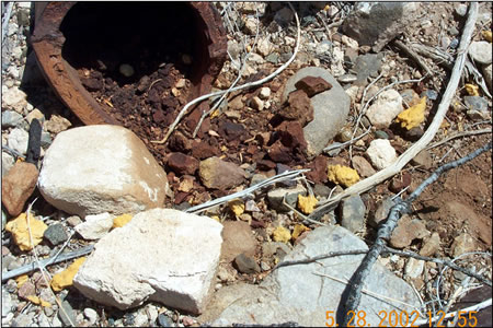 Figure 3.2.  Chunks of main charge, TNT, and remaining casing from the partial detonation of a 155-mm howitzer round found on an active artillery range. Note: Dark orange particles are chunks of TNT.