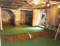 Slab construction using a synthetic base layer into which concrete was poured for homes with basements having dirt floors.